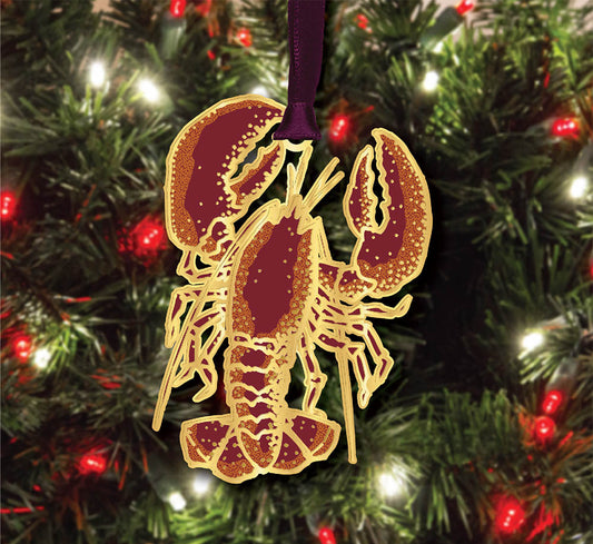 Lobster ornament on a Christmas tree with red berries and lights.