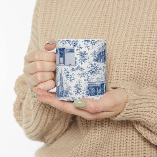 Person holding a mug with blue floral pattern against a beige background