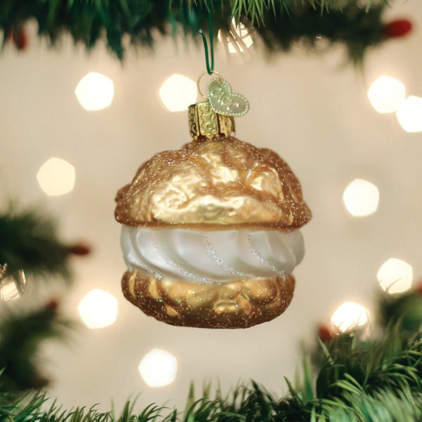 Decorative Christmas ornament shaped like a Cream Puff  hanging on a tree with lights in the background.