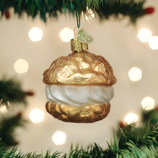 Decorative Christmas ornament shaped like a Cream Puff  hanging on a tree with lights in the background.