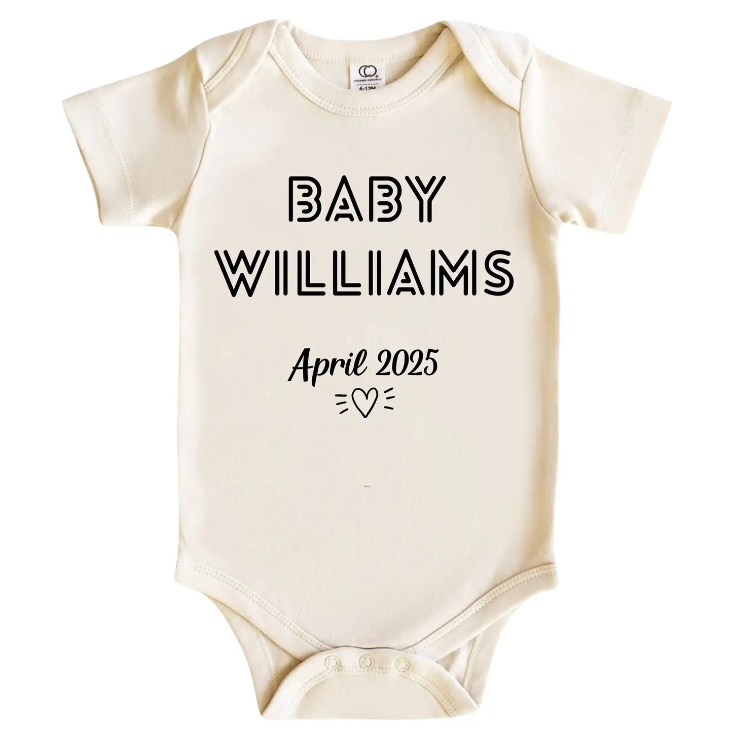 A cream-colored short-sleeve baby bodysuit with 'BABY WILLIAMS' and 'April 2025' printed in black text on the front, displayed against a solid white background.