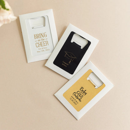 Three personalized bottle openers in packaging on a beige background
