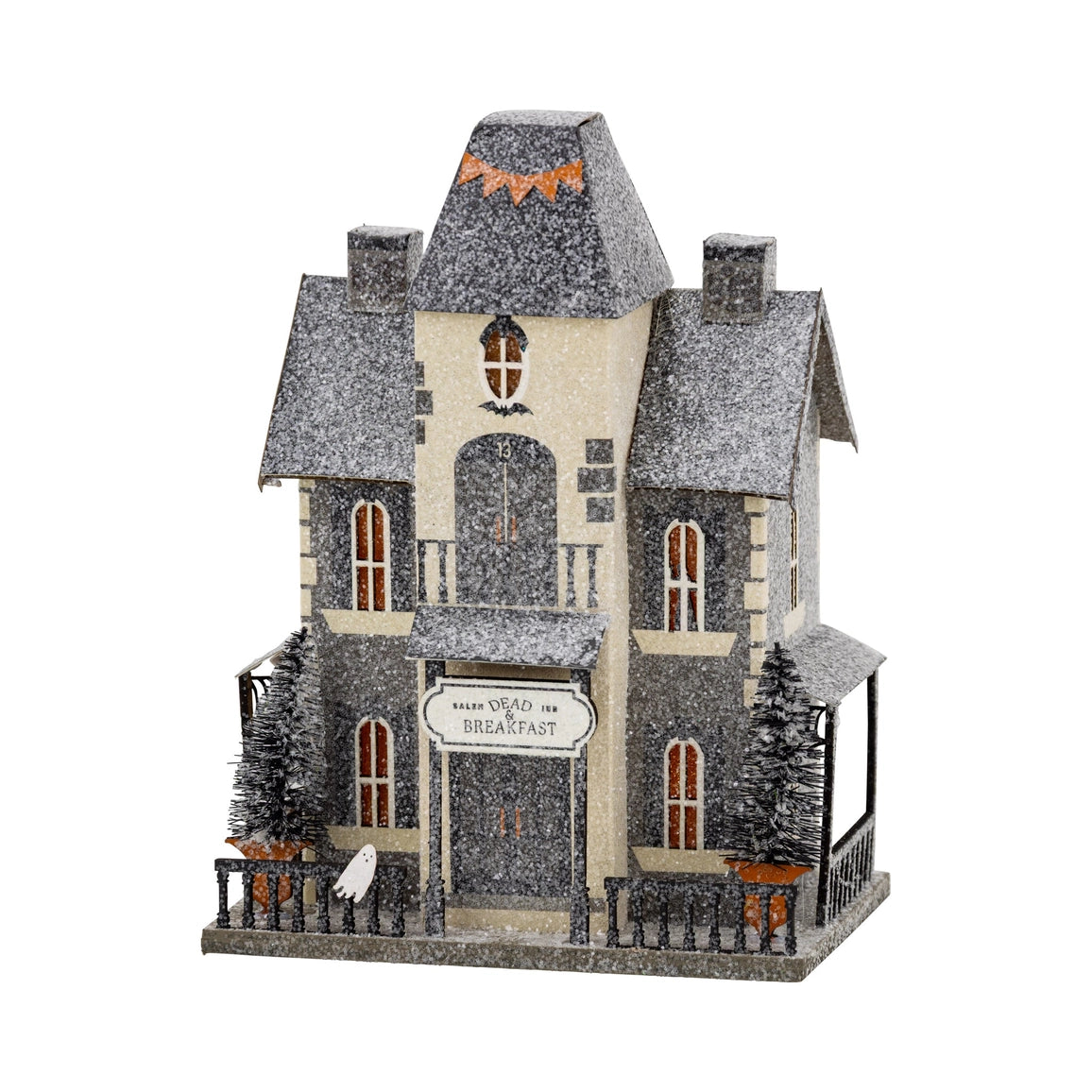 A decorative haunted house holiday ornament with a snow-covered gray and beige exterior, arched front door, small front porch, fence, miniature trees, and a sign reading 'Have You Been My Breakfast?'.