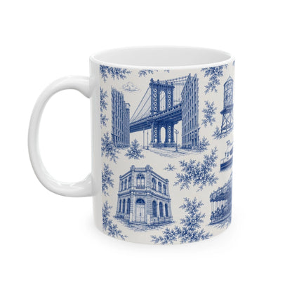 A white ceramic mug featuring a blue toile de Jouy pattern with illustrations of the Brooklyn Bridge, historic buildings, and floral motifs, shown on a plain white background.