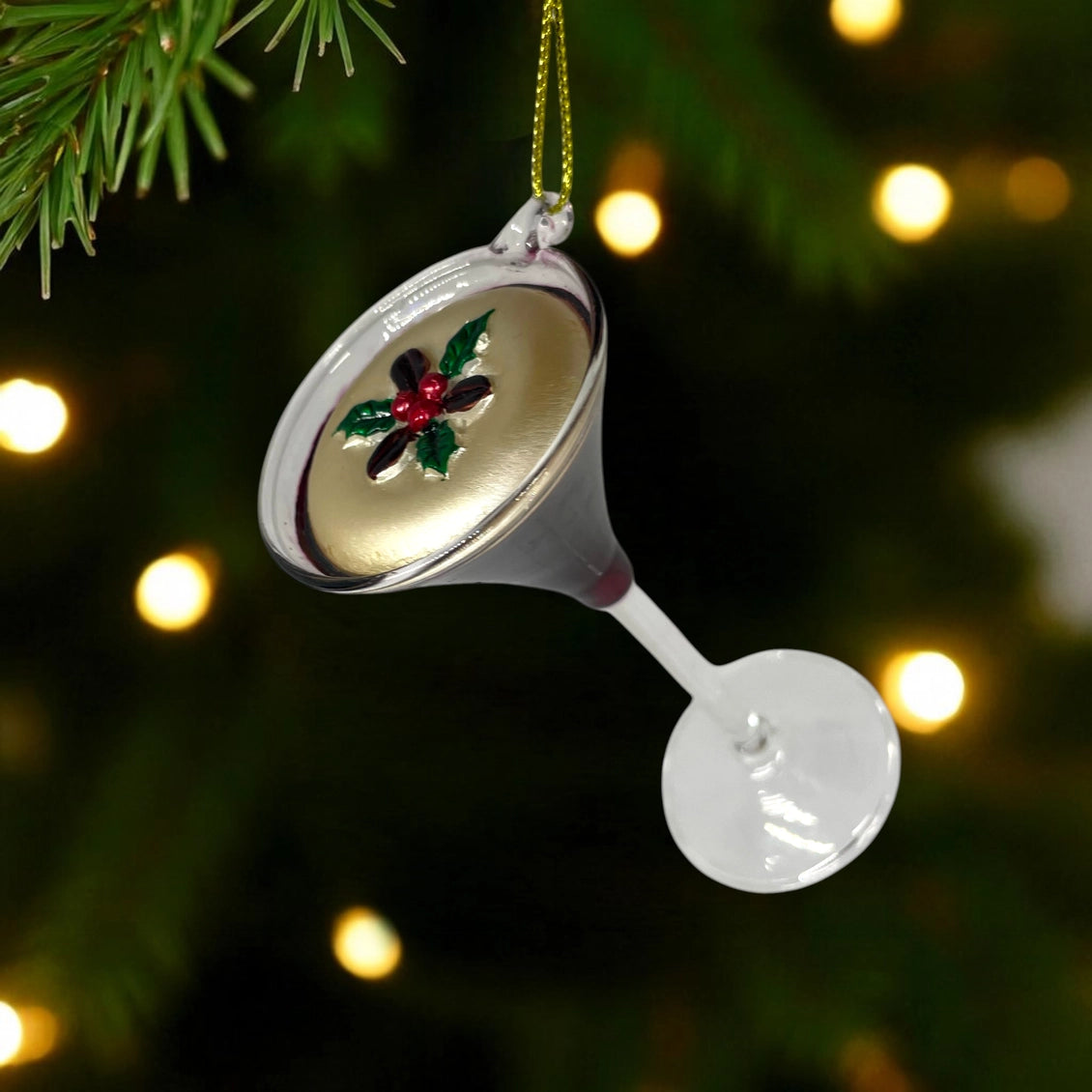 Decorative Christmas ornament shaped like a martini glass with a flower design, hanging against a festive background.