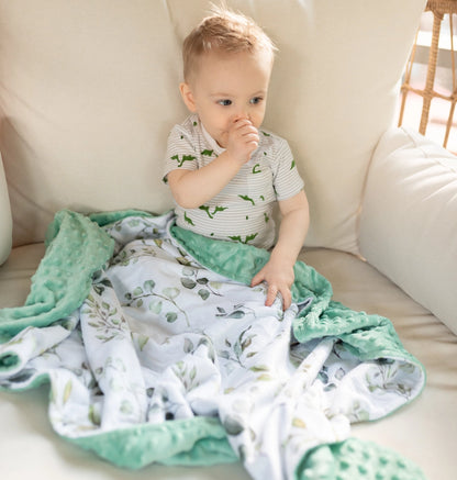 Baby sitting on a couch with a green and white blanket