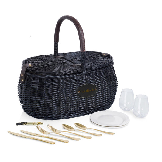 Black wicker picnic basket with cutlery, plates, and glasses on a white background