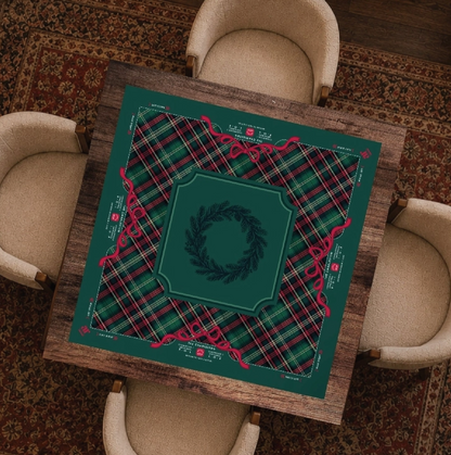 Evergreen & Tartan Christmas Mahjong mat displayed on a game table with classic green tartan plaid, red ribbon bows and evergreen wreath.