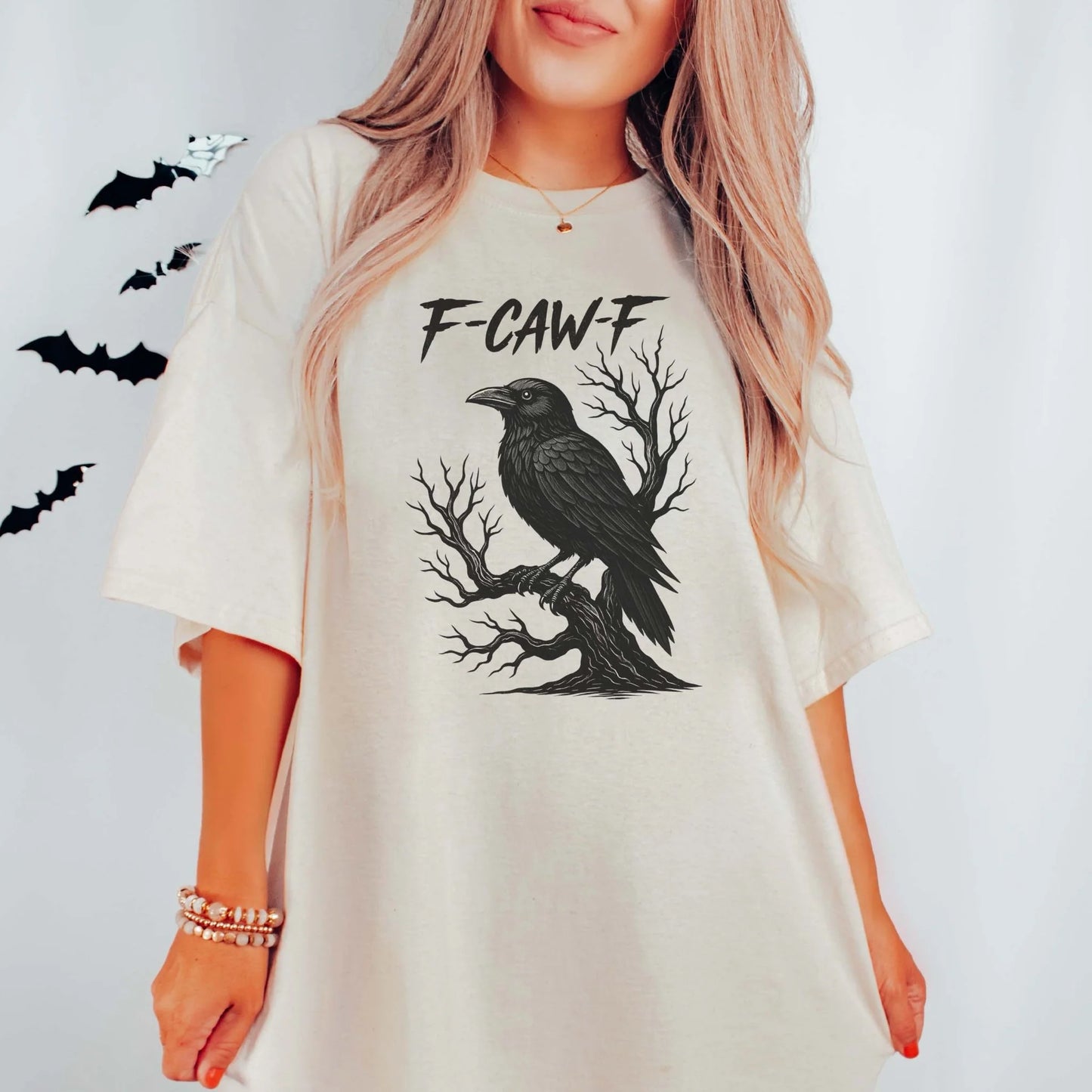 Person wearing a white t-shirt with a black crow design and 'F-CAW-F' text on a light gray background.