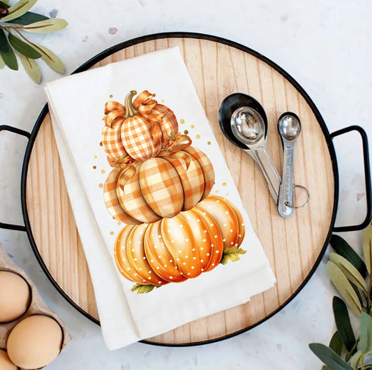 Decorative towel with pumpkins on a wooden board with measuring spoons and eggs.