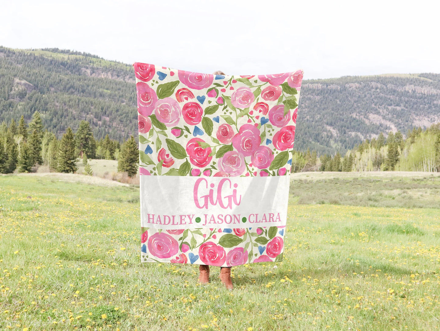 Floral patterned blanket with names held up in a field