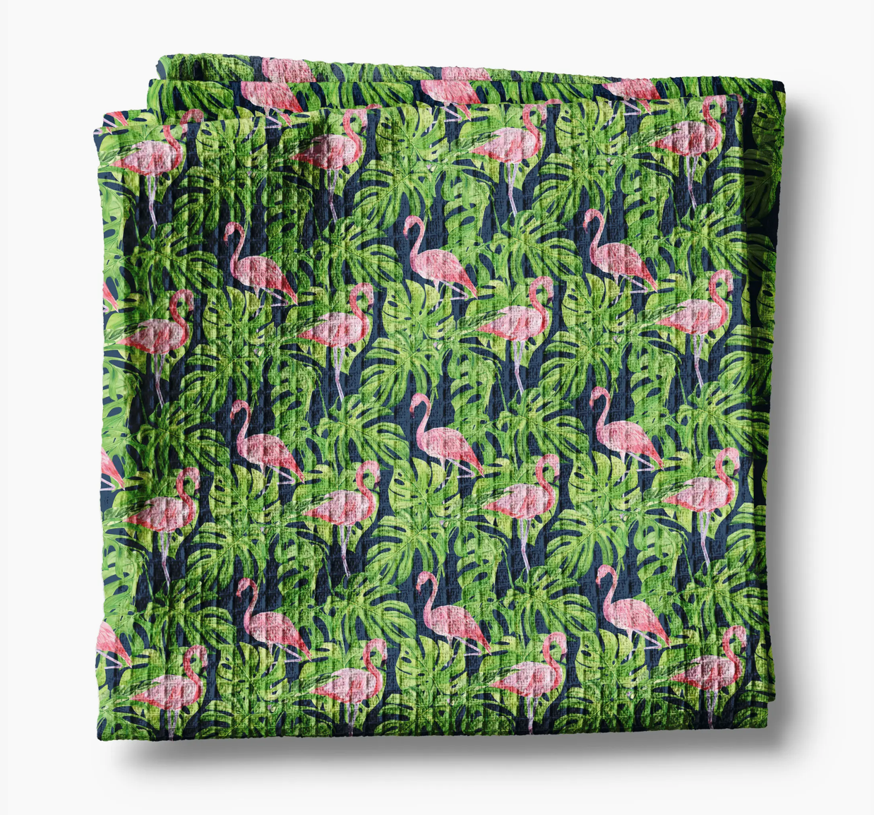 Folded fabric with pink flamingo and green leaf pattern on a white background
