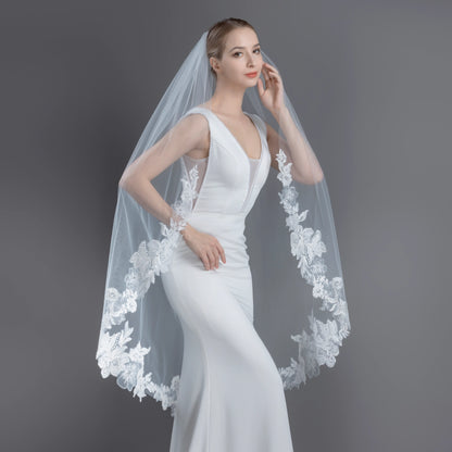 Woman wearing a white wedding dress with a floral veil against a gray background