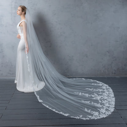 Bride in a white wedding dress with a long, elegant veil against a gray background
