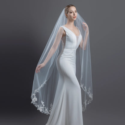 Woman wearing a white wedding dress with a long veil against a dark background