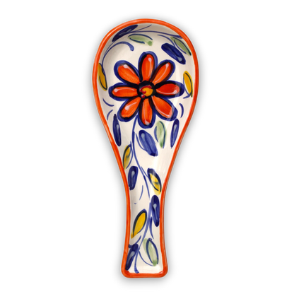 A ceramic spoon rest with a hand-painted floral design, featuring a large orange flower with blue outlines and blue, green, and yellow leaf patterns on a white background, with an orange rim.