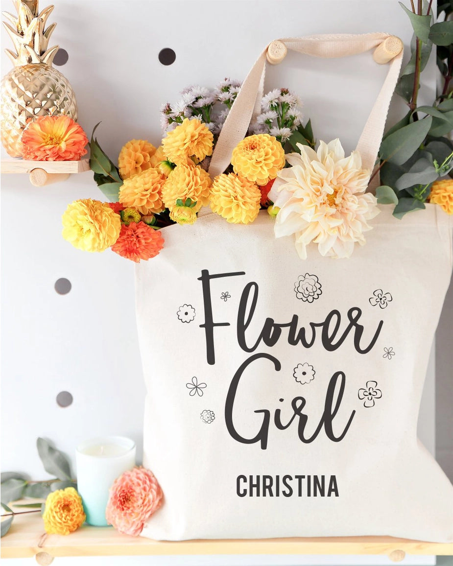 Tote bag with 'Flower Girl Christina' text, surrounded by flowers and decor.