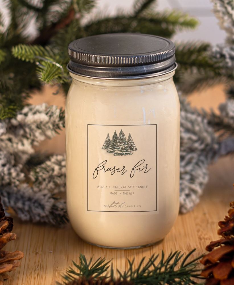 Close-up of Fraser Fir candle label featuring an illustrated snow-covered evergreen forest.