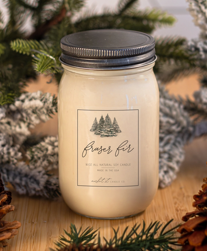 Close-up of Fraser Fir candle label featuring an illustrated snow-covered evergreen forest.