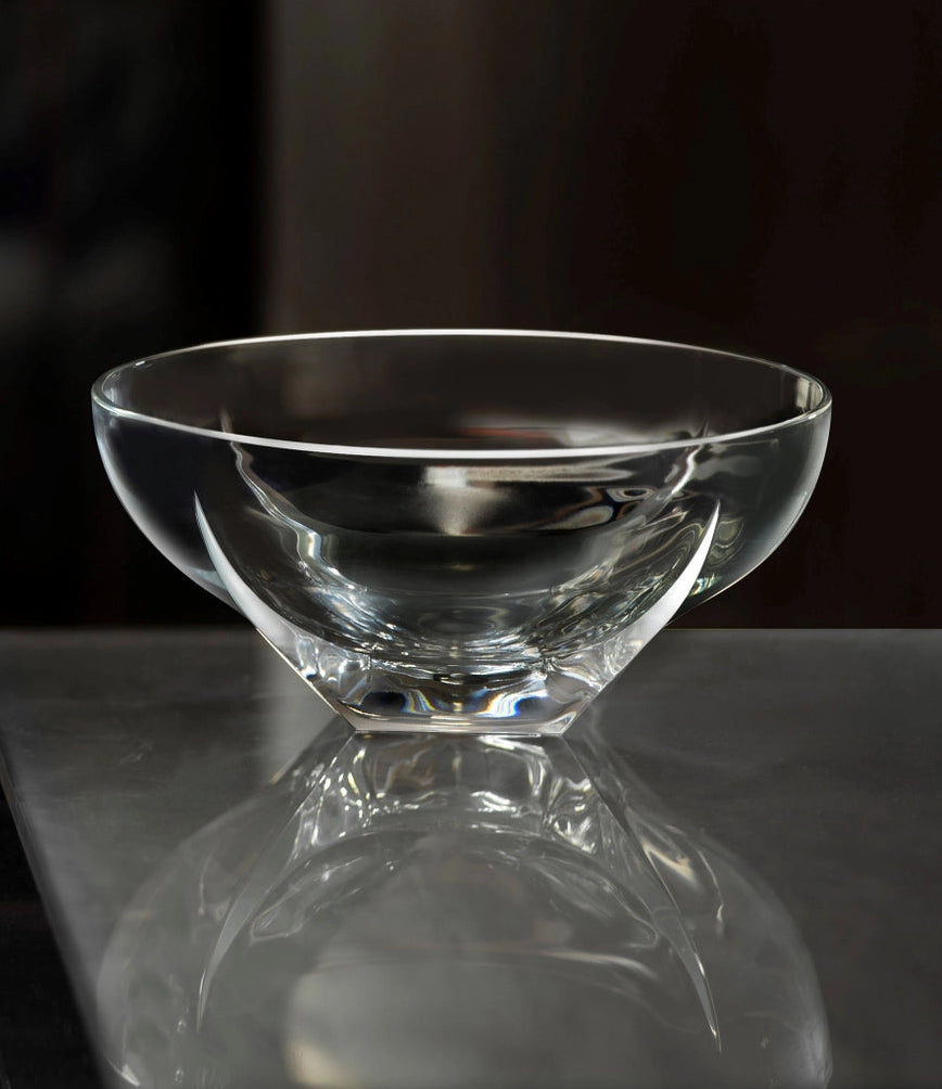 Clear glass bowl on a reflective surface with a dark background