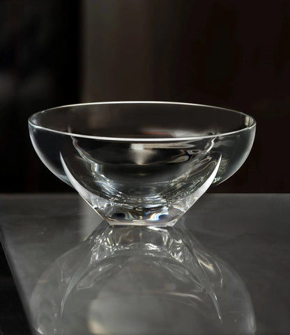 Clear glass bowl on a reflective surface with a dark background