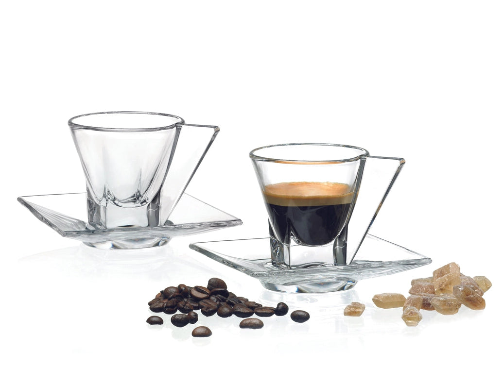 Two glass espresso cups with saucers, coffee beans, and sugar on a white background