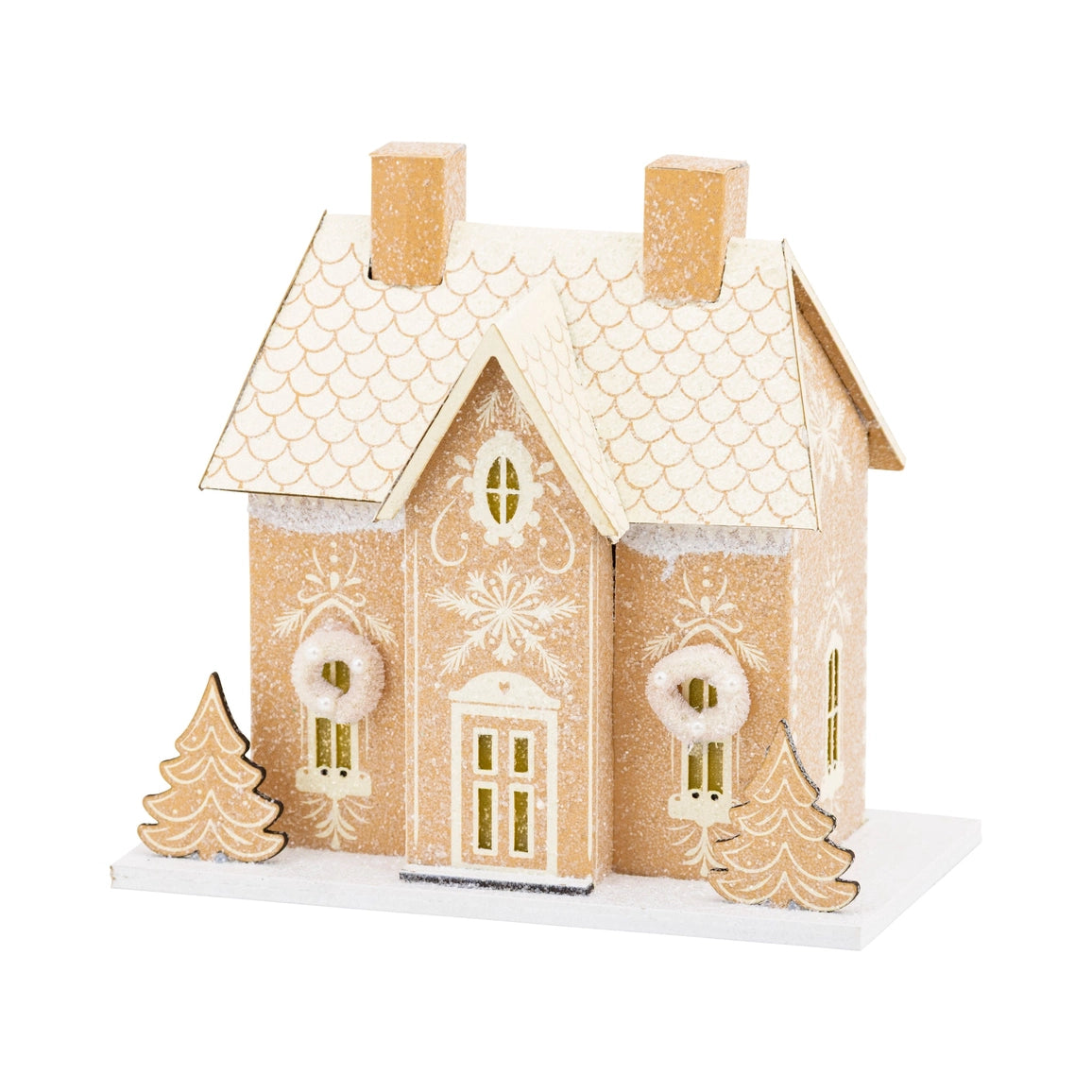 A decorative gingerbread-style house ornament with a scalloped roof, snowflake details, two chimneys, two small tree decorations, and a white base, shown on a plain white background.