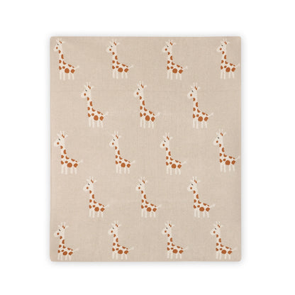 A square fabric item, likely a blanket or throw, featuring a repeating pattern of cartoon giraffes in brown and white on a warm beige background.