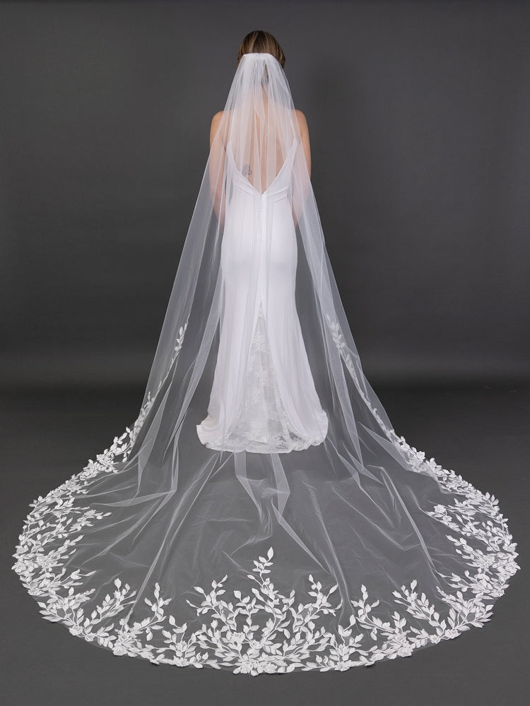 White wedding dress with a long, embroidered veil on a dark background
