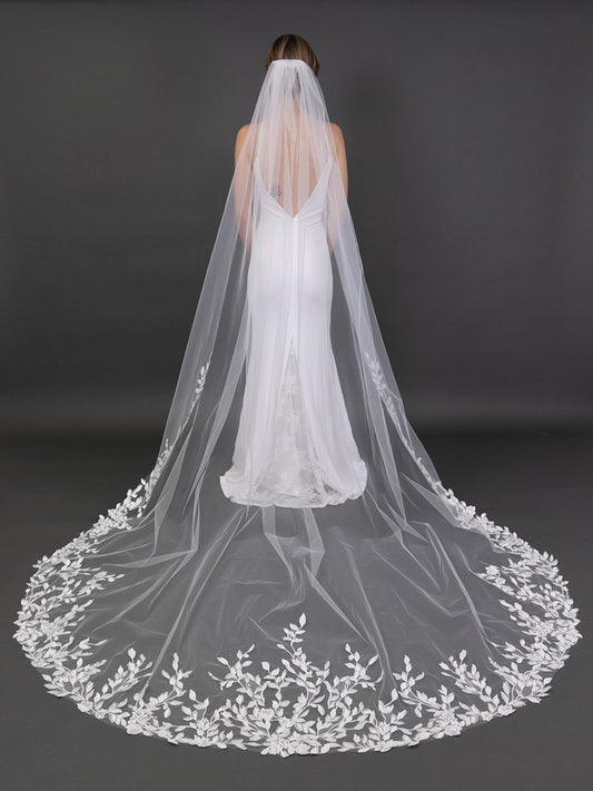 White wedding dress with a long, embroidered veil on a dark background