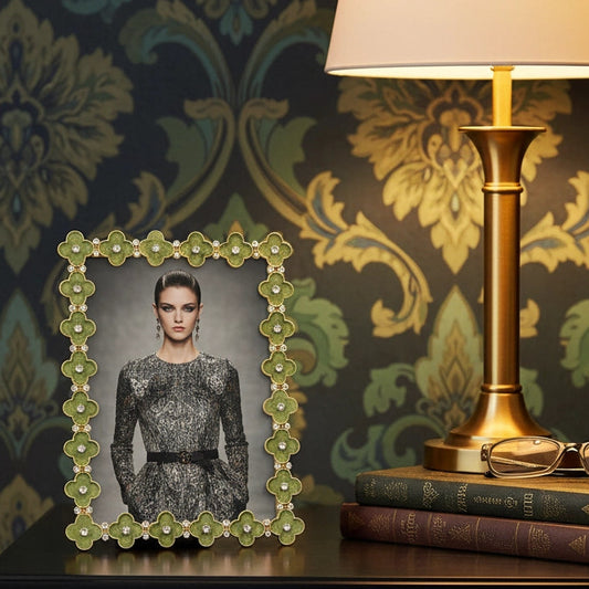Framed portrait on a nightstand with a lamp and books against decorative wallpaper.