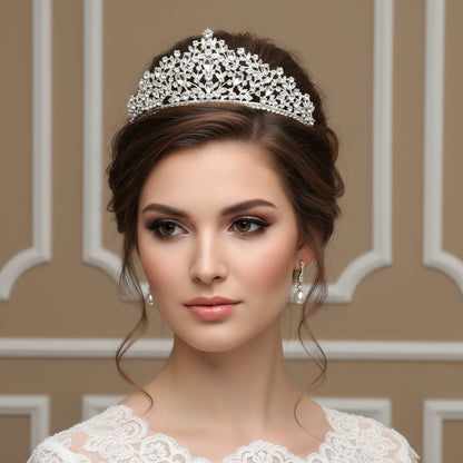Woman wearing a silver tiara and earrings against a beige wall.