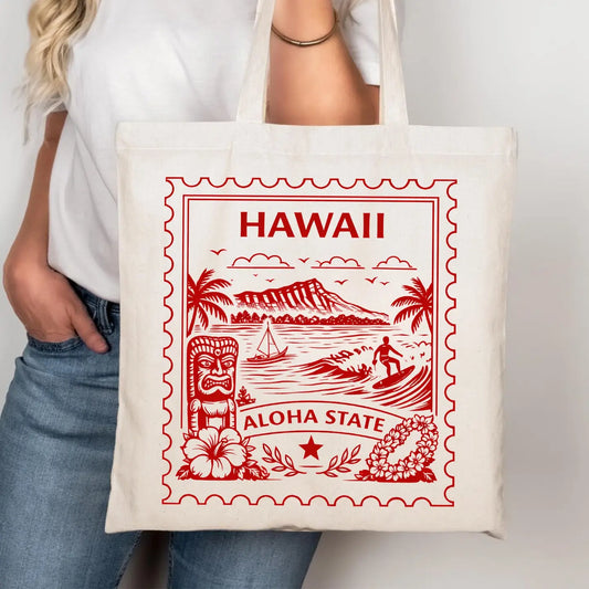 Tote bag with red Hawaii-themed design held by a person wearing a white shirt and blue jeans.