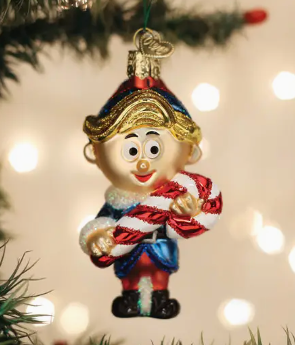 Christmas ornament of a elf holding a candy cane on a decorated tree.