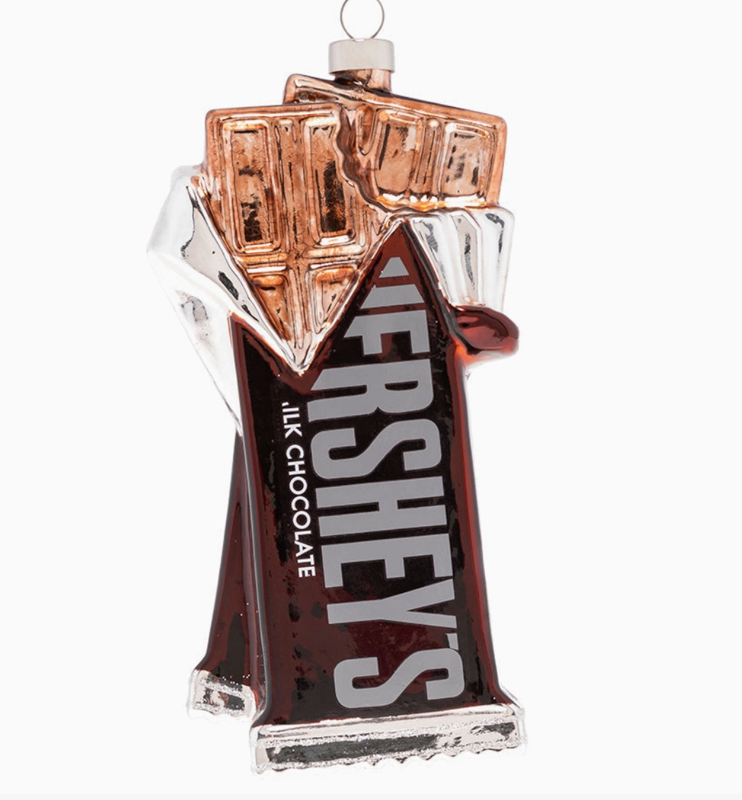 A Hershey's milk chocolate bar shaped ornament or figurine, featuring the classic brown wrapper with white 'HERSHEY'S' lettering, a silver foil-wrapped chocolate bar, and a small hanging loop at the top, shown on a plain white background.