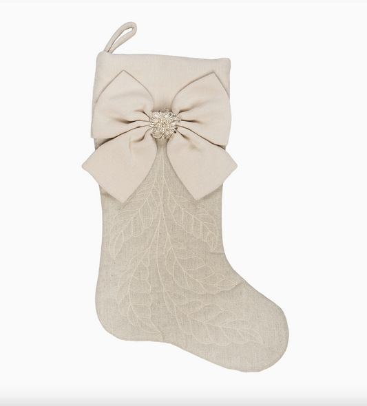 Elegant ivory Christmas stocking with embroidered foliage, oversized off-white bow, decorative pearl and beaded center, and fabric hanging loop.