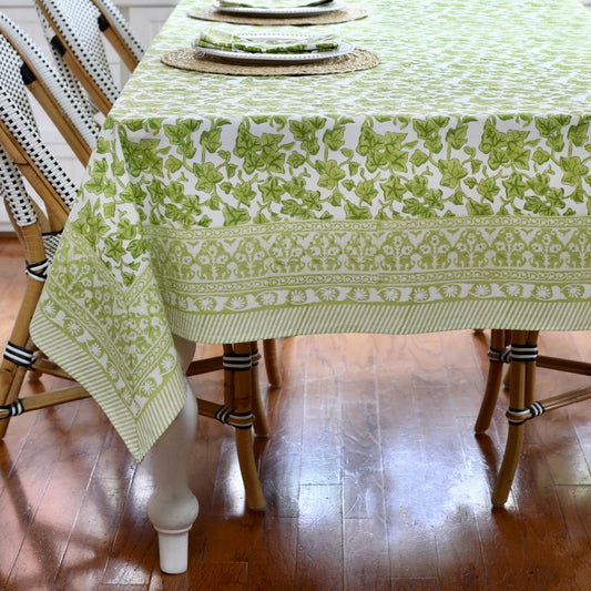 Green and white patterned tablecloth on a wooden table with chairs.