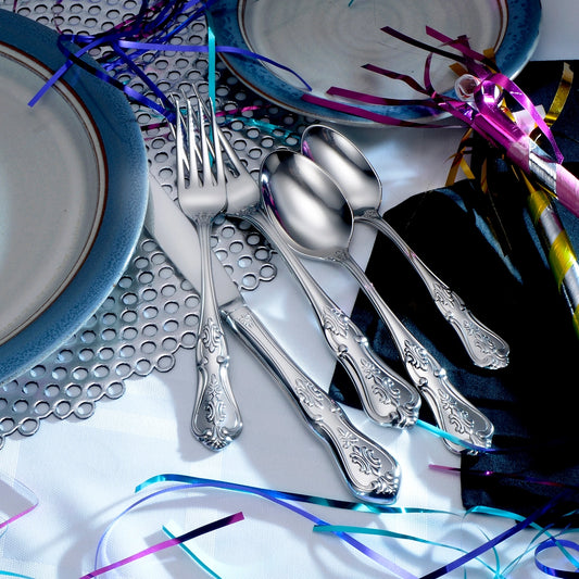 Silver flatware set on a decorative table with colorful streamers and plates.