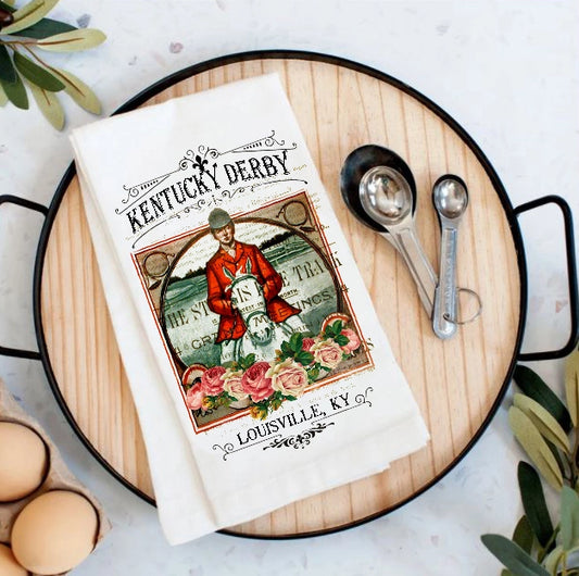 Kentucky Derby-themed towel on a wooden board with measuring spoons and eggs.