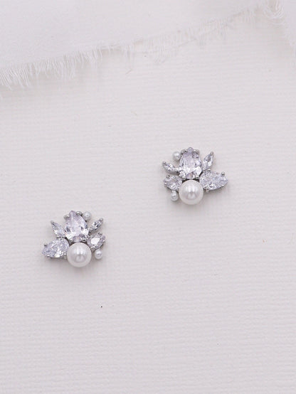 Pair of silver earrings with pearls and clear stones on a white background