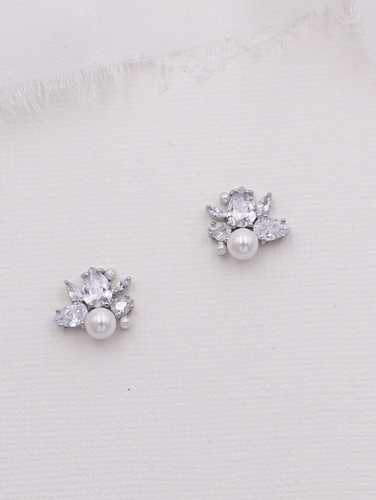 Pair of silver earrings with pearls and clear stones on a white background