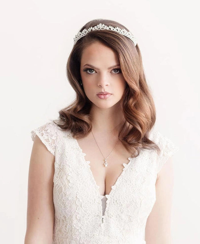 Woman wearing a white lace dress and tiara on a plain background