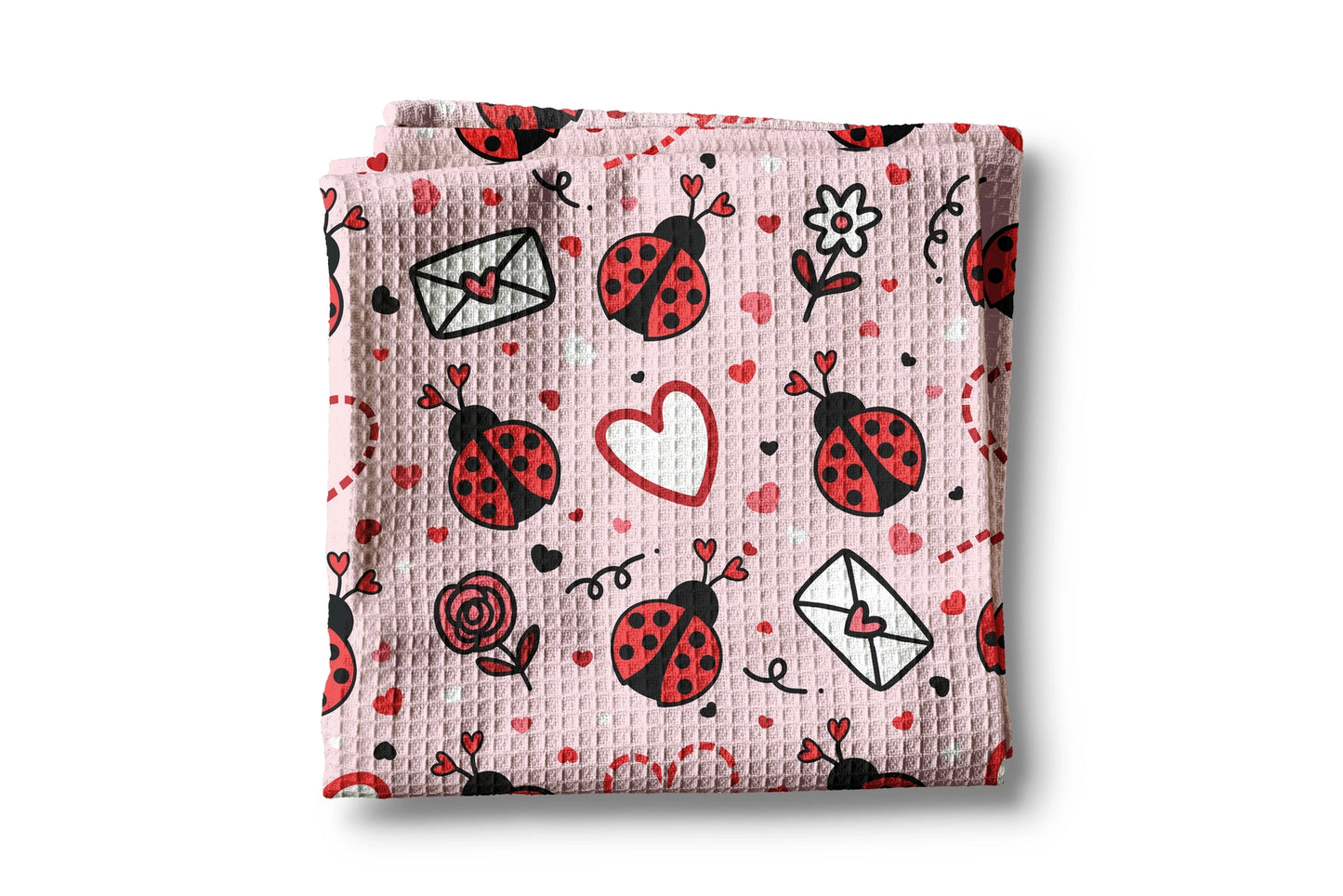 Folded pink blanket with ladybug and heart patterns on a white background