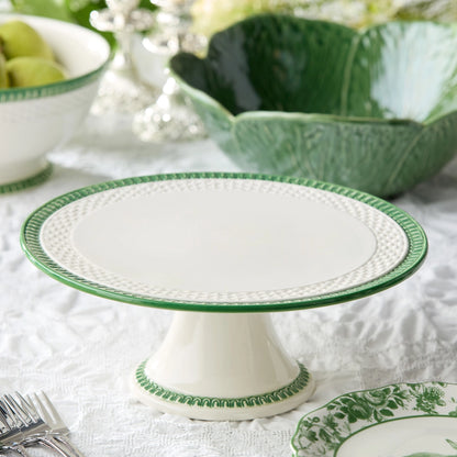 White cake stand with green decorative edge on a table setting.