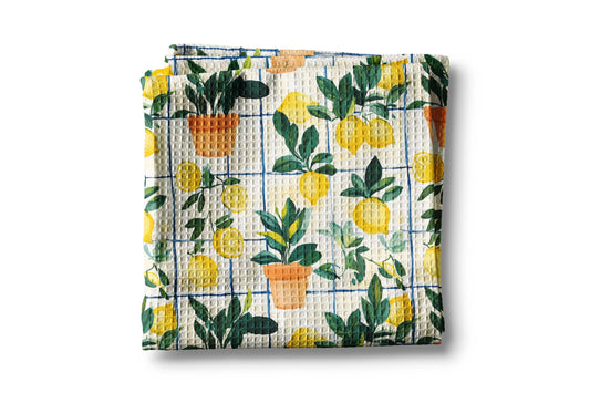 Folded waffle towel with lemon and potted plant pattern on a white background