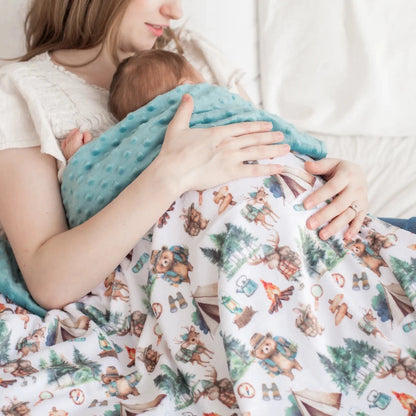 Woman holding a baby wrapped in a blanket with bear and nature pattern