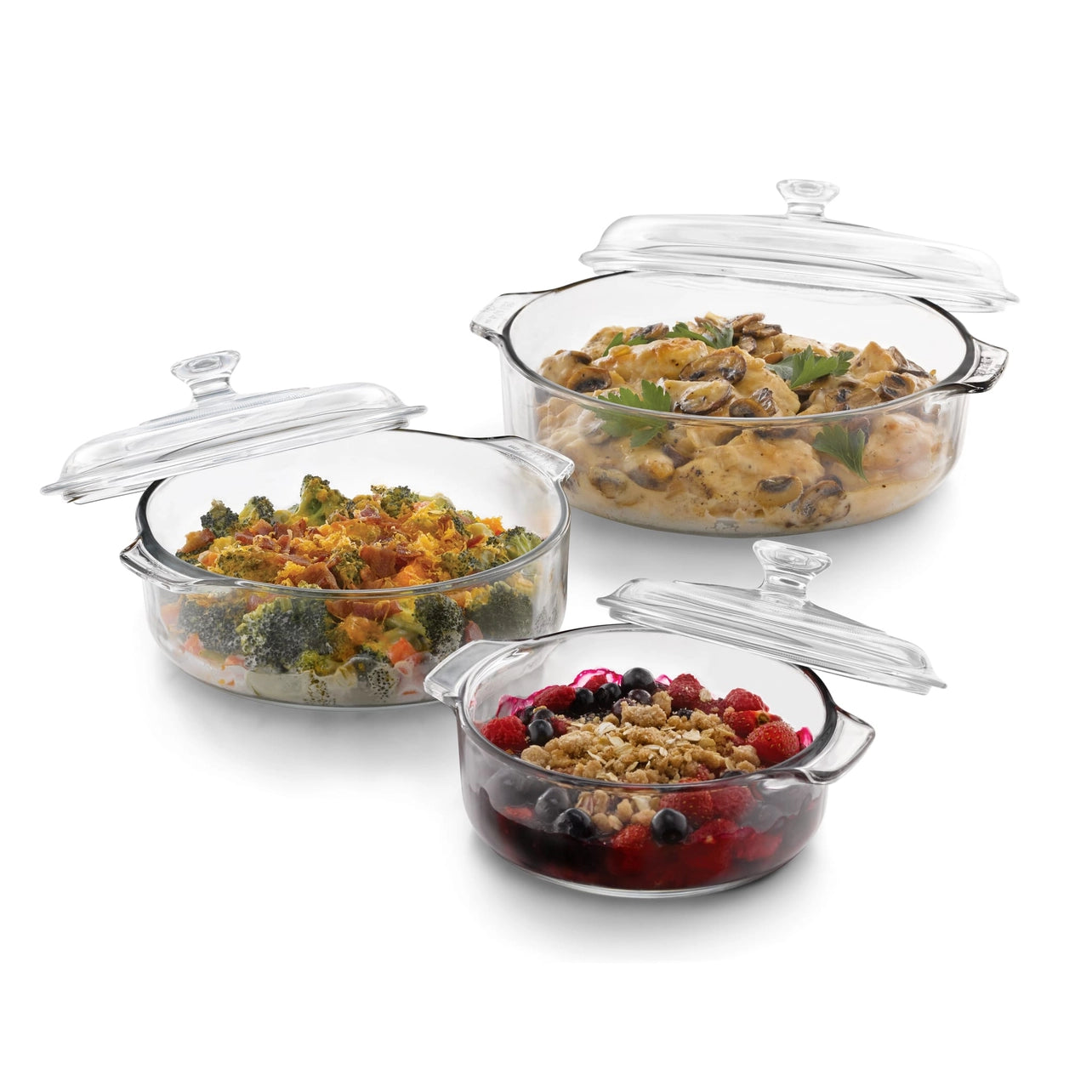 Set of glass baking dishes with food inside on a white background