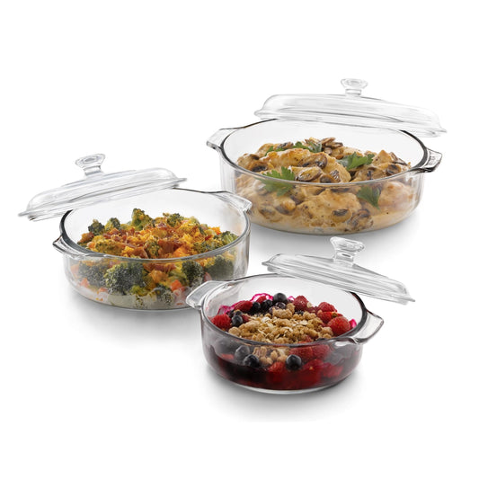 Set of glass baking dishes with food inside on a white background