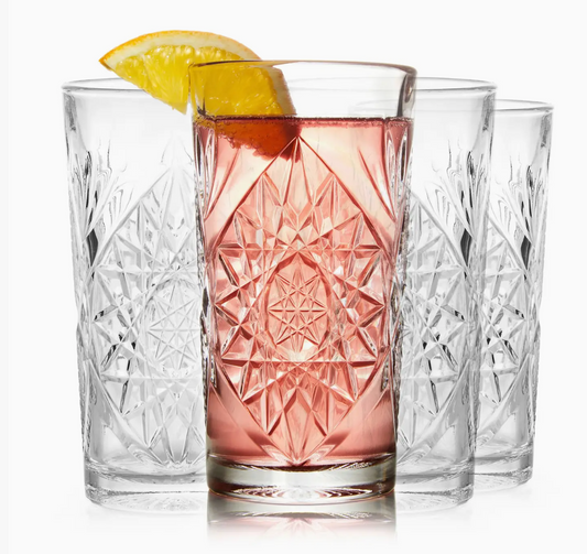 Set of four crystal glasses with a pink drink and lemon slices on a white background