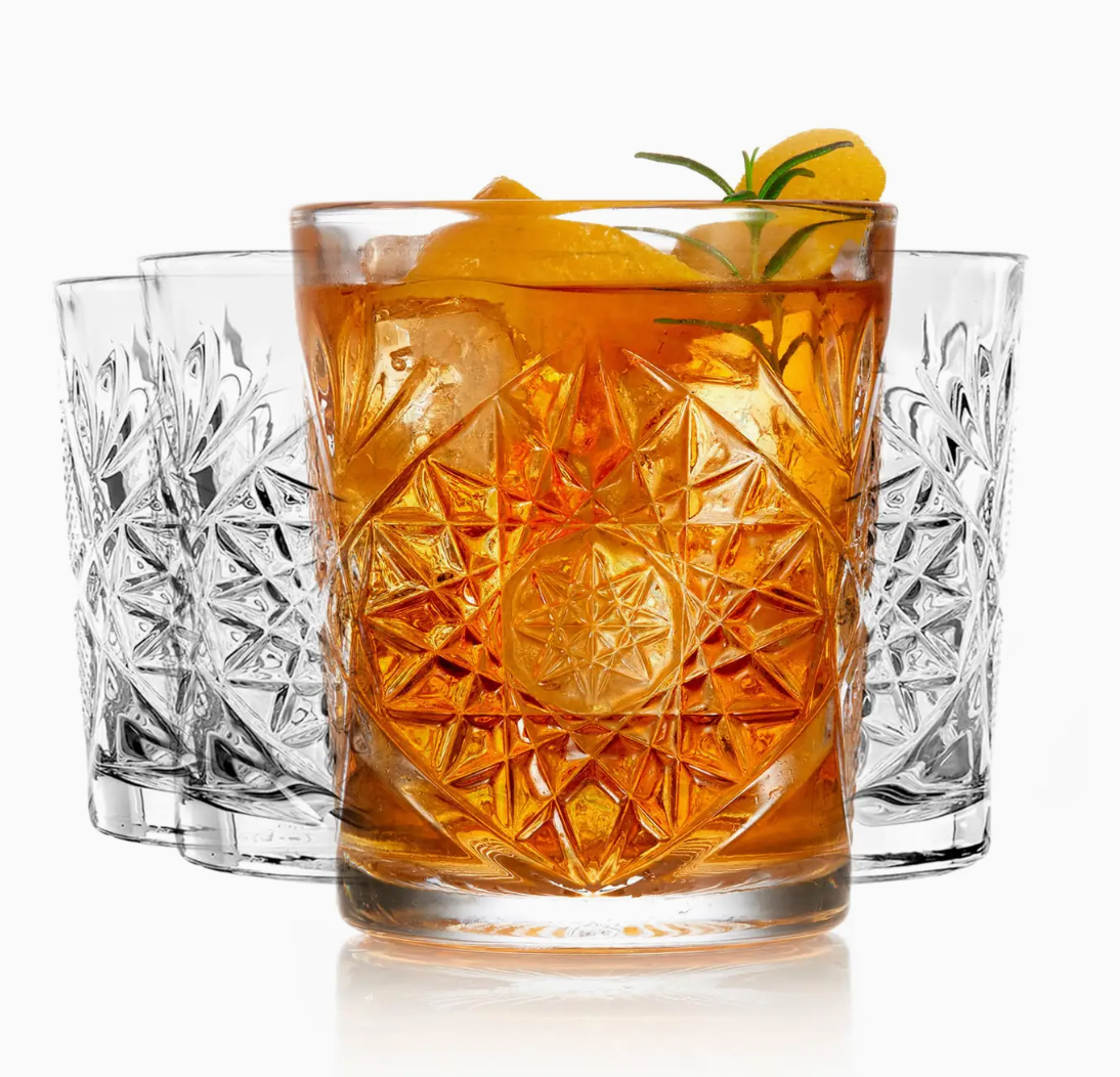 Decorative glass with a cocktail and garnish, surrounded by other glasses on a white background